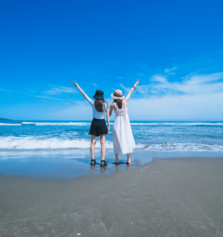 女性二人が砂浜でポーズをとっている写真